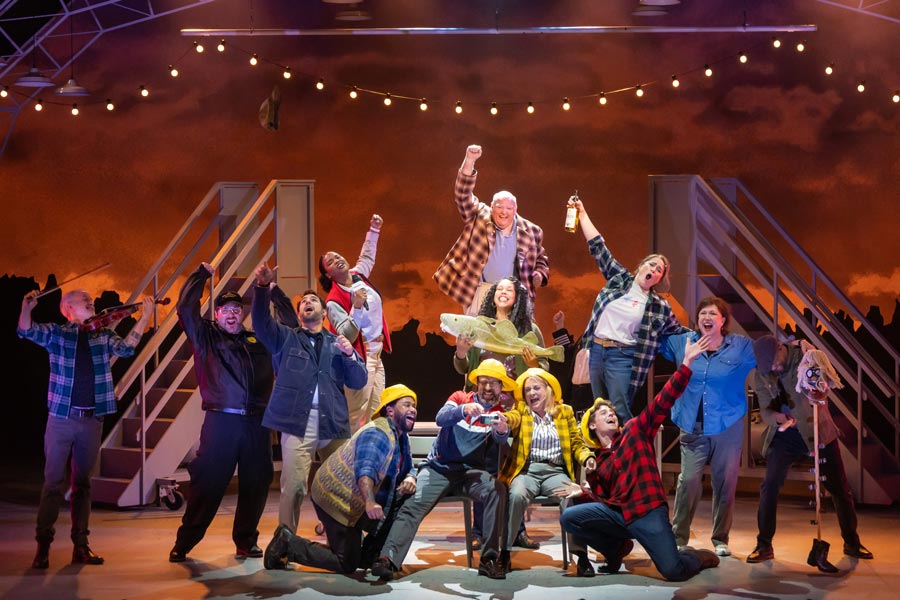 A group of actors on a stage acting out a rousing bar scene. 