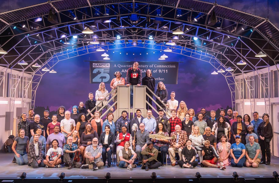 A large group of people gathered on a stage, smiling and posed for an image.